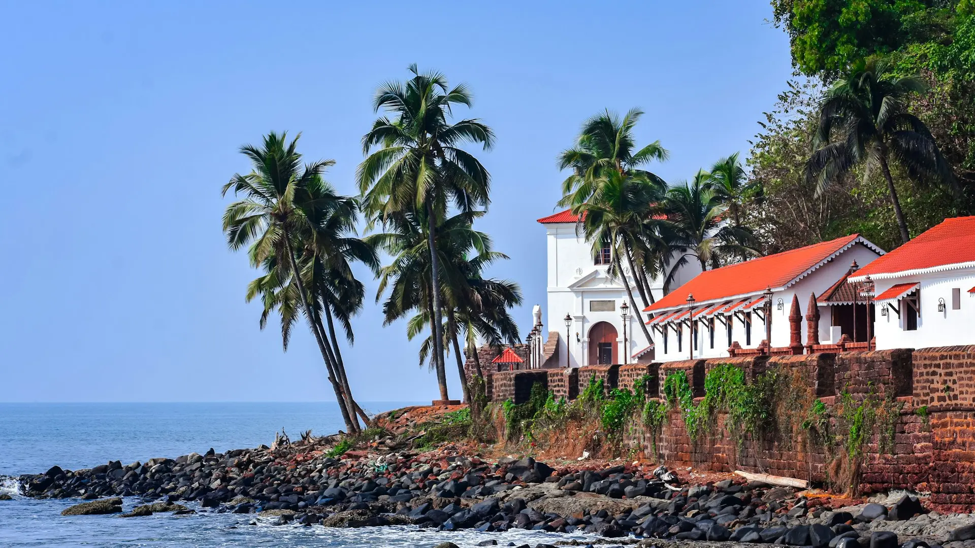 a white building with a red roof next to a body of water